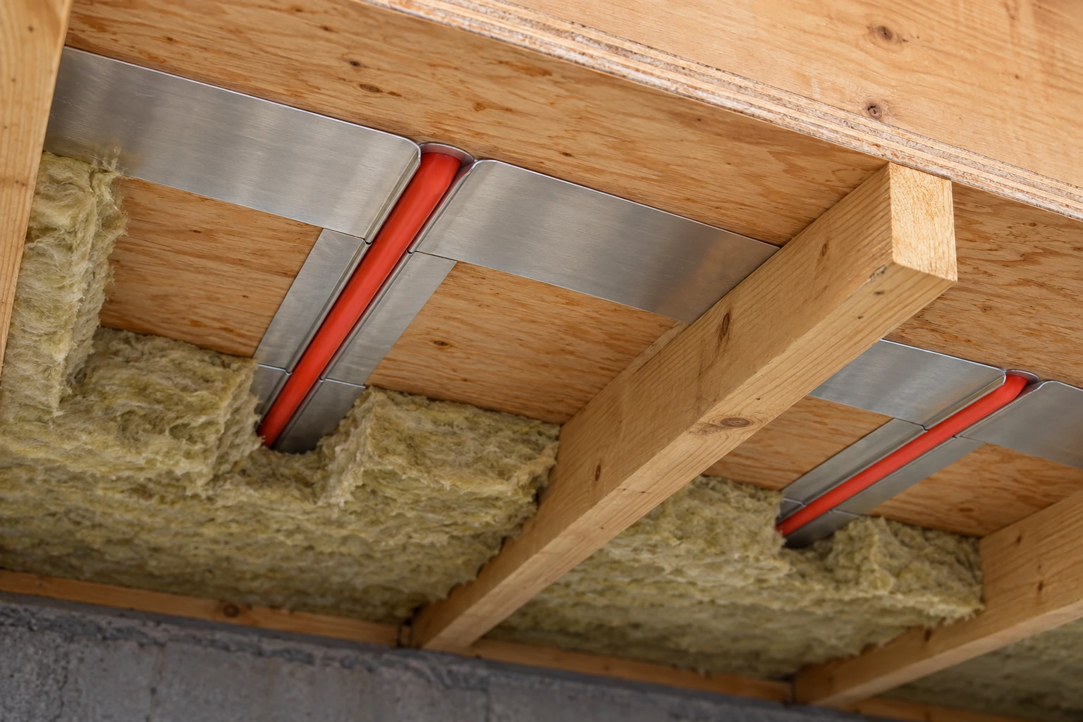 Tubing seated in an aluminum plate whose broad wings contact the plywood underside.
